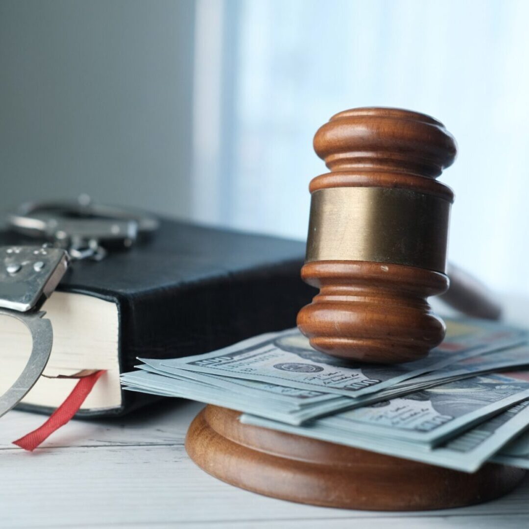 Gavel, handcuffs, and money on book.